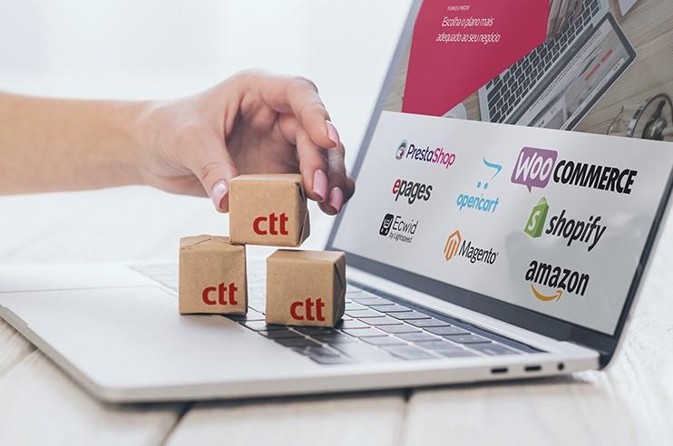 Laptop aberto com pequenas caixas de cartão que têm o logótipo dos CTT
